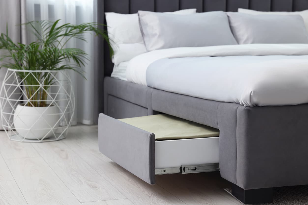Hotel bed base with integrated storage drawer, upholstered frame designed for practical hotel room use.