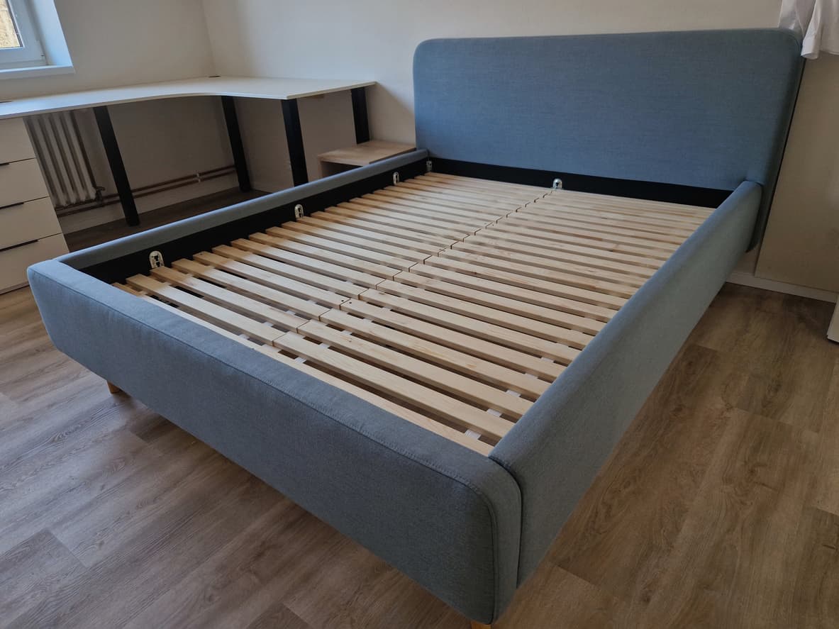 Hotel bed base with upholstered frame and wooden slat system, designed for durable hotel room use.