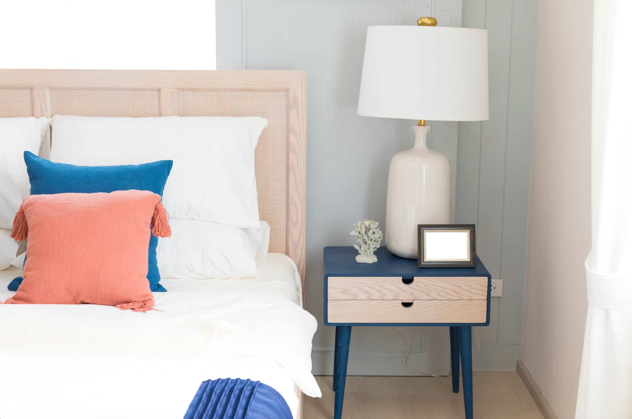 Hotel headboard with wooden frame and upholstered panel, paired with modern bedside table and lamp for hotel rooms.