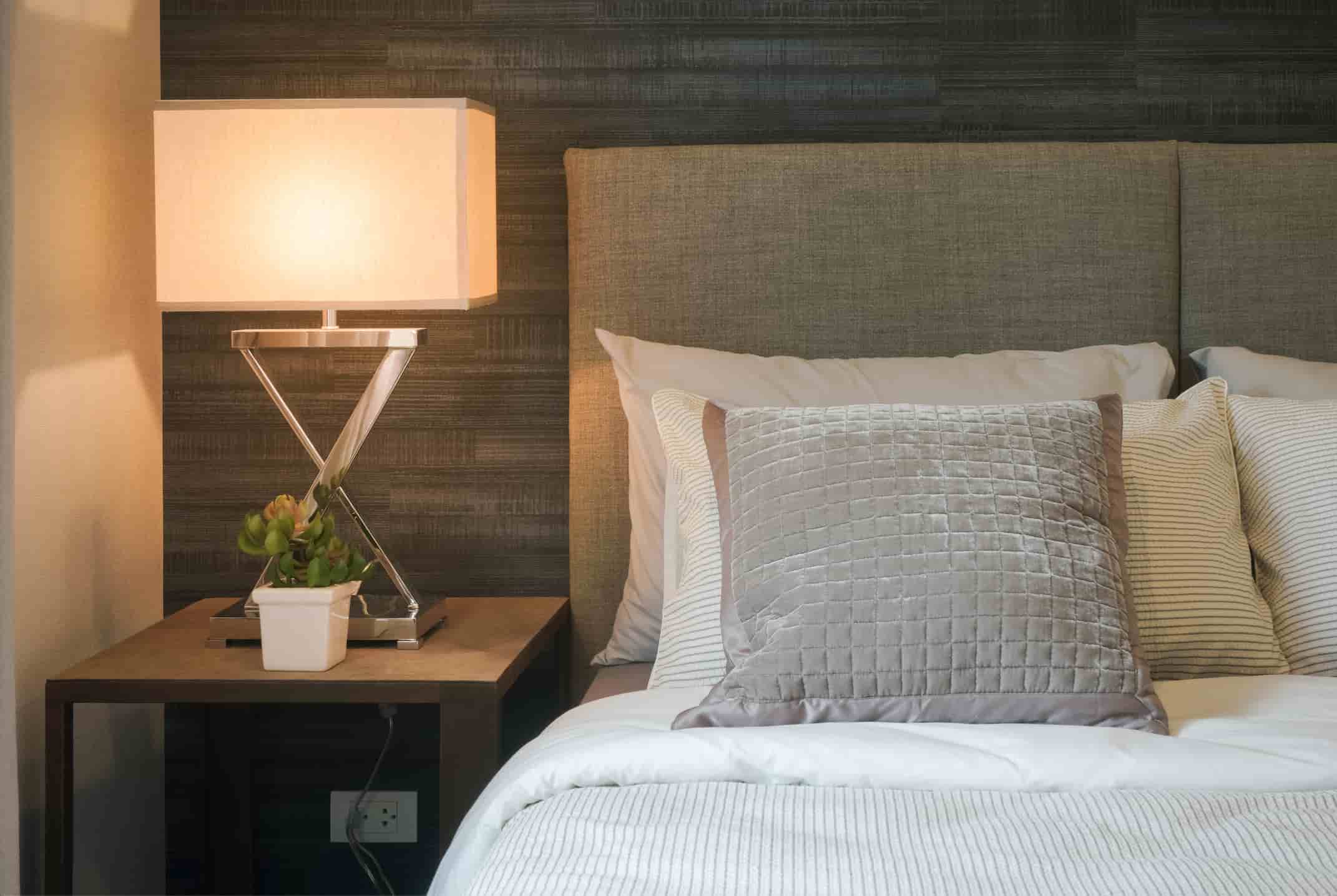 “Hotel headboard with upholstered fabric panel, bedside table and modern lamp designed for hotel guest rooms.