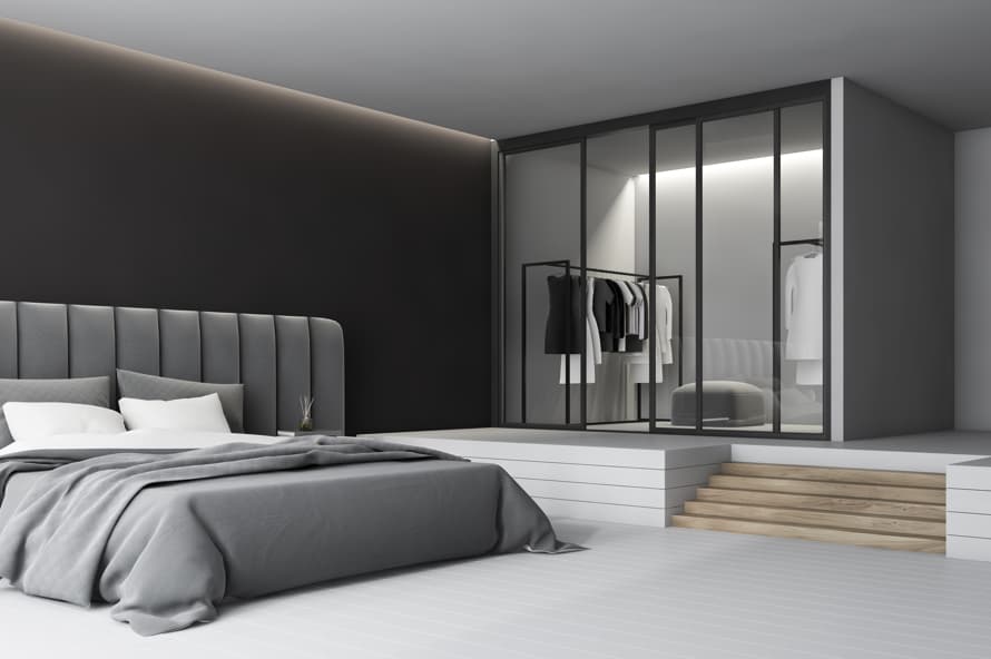 Modern hotel suite bedroom with upholstered headboard, open wardrobe, and minimalist interior design